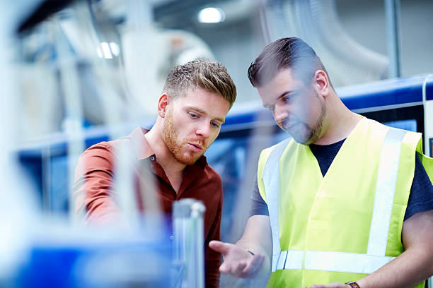 Manager et ouvrier regardant une machine sur une chaine de production